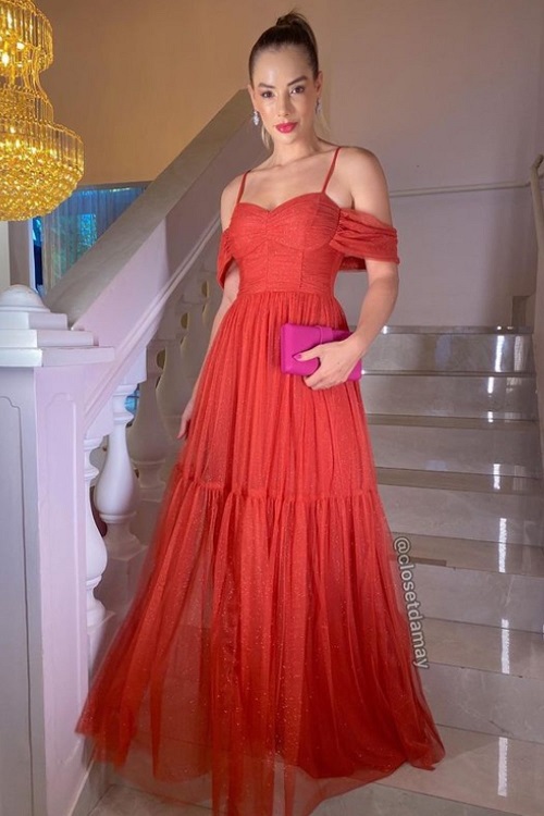 Woman in a terracotta dress with a fuchsia clutch bag