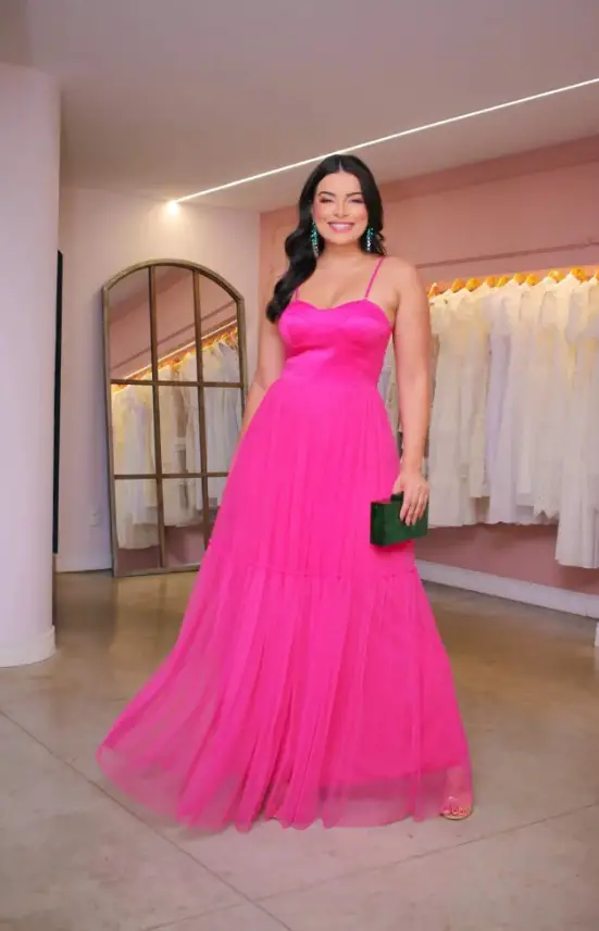 Woman in a pink dress with an emerald green clutch bag