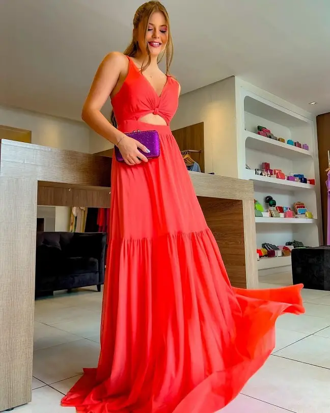 Woman in a coral dress with a purple clutch bag