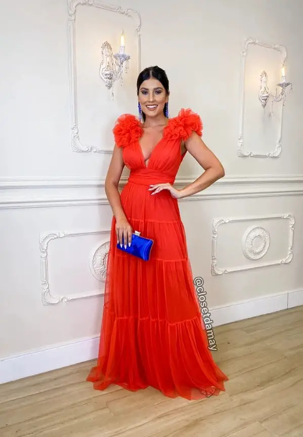 Woman in a coral dress with a blue clutch bag